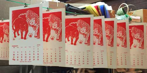 Row of silk screened calendar pages hanging to dry.